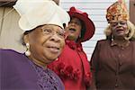 Three senior women in fine dresses and fancy hats.