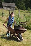 Girl pushing a wheelbarrow in the garden.