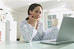 Woman in pajamas working at a laptop computer.