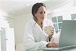 Woman in a bathrobe types at a laptop.