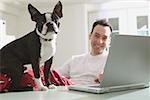 A man and his dog, work on a laptop computer.