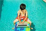 Jeune travaillant sur son ordinateur portable à bord de la piscine