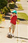 A young skateboarder talking on his mobile phone