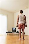 A middle-age man lifting weights while watching TV