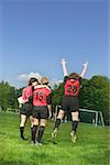 Three female soccer players celebrate a win