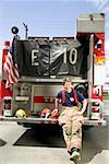 Female firefighter sitting on a fire truck