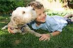 Boy and dog lying down together outdoors