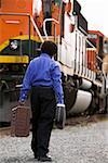 Boy walking beside train with baggage