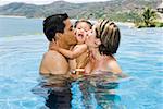 Parents s'embrasser enfant en bas âge dans la piscine tropicale