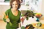 Smiling woman with vegetables in kitchen