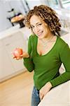 Portrait of woman with apple in kitchen