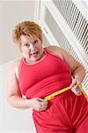 Upset overweight woman measuring waist