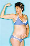 Pregnant woman in bikini flexing bicep