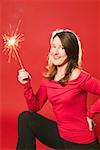 Smiling woman holding burning sparkler