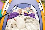 Young girls sleeping in tent with dog