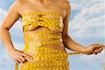 Midsection of nude woman wrapped in measuring tape