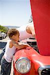 Father and son checking under car hood