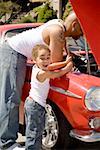 Young boy holding tools for his mechanic father