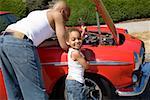 Young boy helping his father work on car