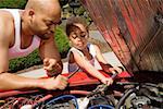 Young boy helping his father work on car