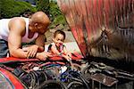 Young boy helping his father work on car