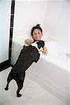 Dog licking woman in bathtub