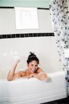 Woman playing with bubbles in bathtub