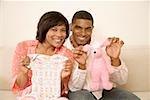Couple displaying baby clothes