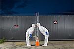 People in biohazard suits kissing over orange safety cone