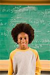 Portrait of boy in front of math on blackboard
