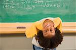 Boy bending over backward in front of blackboard