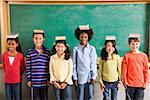 Row of students with books on their heads in classroom