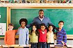 Portrait of male teacher and students in classroom