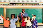 Male teacher and students cheering in classroom