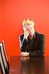 Businessman wearing gold crown in conference room