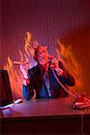 Businessman dressed as devil talking on telephone