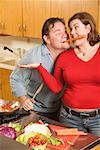 Couple playing with food while cooking