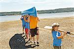 Male camp counselor and children carrying canoe