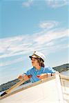 Boy wearing ship captain’s hat in row boat