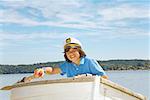 Boy wearing ship captain’s hat in row boat