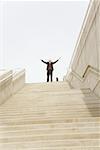 Businessman with arms raised at top of steps