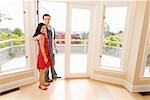 Hispanic couple standing in doorway of new house