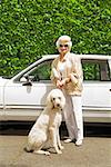 Senior woman and dog next to car