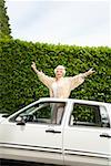 Senior woman standing in sunroof of car