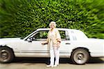 Senior woman standing next to car