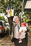 Kaufmann Holding Baby an Bushaltestelle