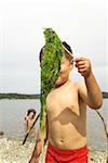 Boy holding stick with seaweed