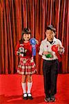 Asian girl and boy holding prize ribbons on stage