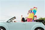 African woman in convertible with shopping bags