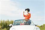 African woman reading map in convertible car